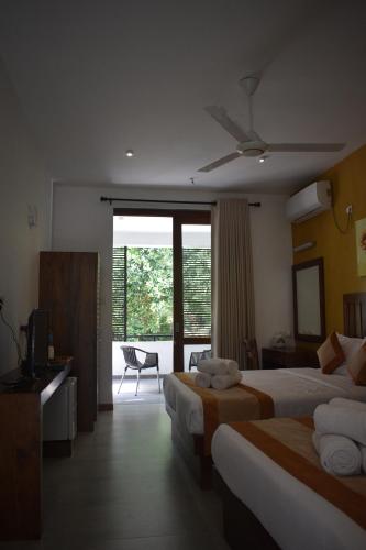 a hotel room with two beds and a television at Lotus Lake Residence in Kandy