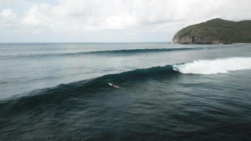 a person riding a wave in the ocean at Baha Baha Villas West Sumbawa Yoyos Wellness Center, Gym, Yoga, Skate Park, Bar & Cafe in Sekongkang