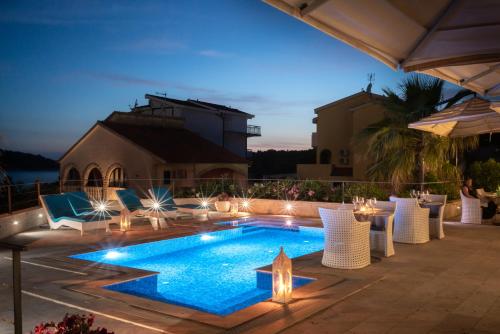 eine Terrasse mit Pool und Stühlen sowie ein Gebäude in der Unterkunft Boutique Hotel Life in Rogoznica