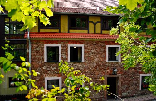 スレブルナ・グラにあるCentrum Turystyki Niekonwencjonalnejの白い窓と木々が並ぶ古いレンガ造りの建物