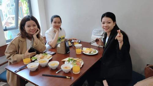a group of three women sitting at a table eating food at Peaceful House Hostel in Dong Hoi