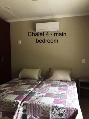a bedroom with a bed with the words chalk main bedroom at Impala Chalets in Phalaborwa