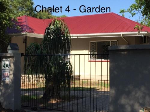 a house with a gate with a palm tree in it at Impala Chalets in Phalaborwa
