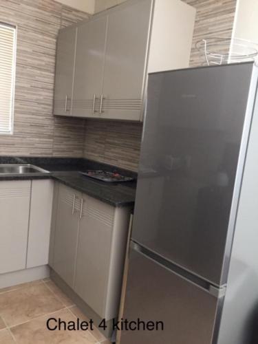 a kitchen with white cabinets and a stainless steel refrigerator at Impala Chalets in Phalaborwa