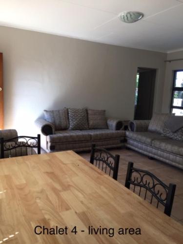 a living room with a wooden table and chairs at Impala Chalets in Phalaborwa