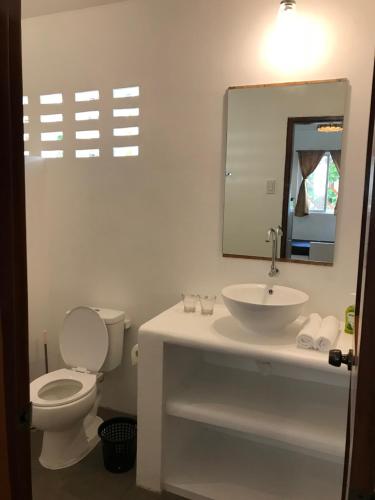 a bathroom with a toilet and a sink and a mirror at The Broken Board in General Luna
