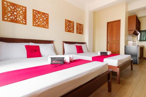 Duas camas num quarto com almofadas vermelhas em RedDoorz Plus near Johnson and Johnson Paranaque em Manila