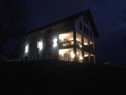 a house with lights on the side of it at night at Popasul din Pietrar in Preluca Veche