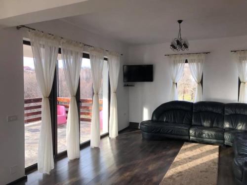 a living room with a black leather couch and windows at Popasul din Pietrar in Preluca Veche