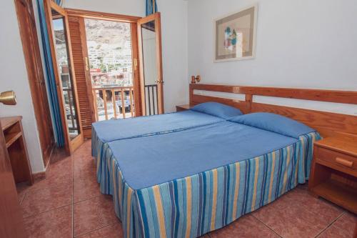 una camera con un letto blu e una finestra di Montecarlo Apartamento40 a Puerto Rico de Gran Canaria