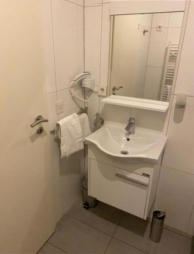 a white bathroom with a sink and a mirror at Kispet Deluxe Hotels&Suites in Oberhausen