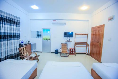 a living room with two beds and a tv at Sunstar Nilaveli in Trincomalee