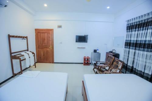 a room with two beds and a wooden door at Sunstar Nilaveli in Trincomalee