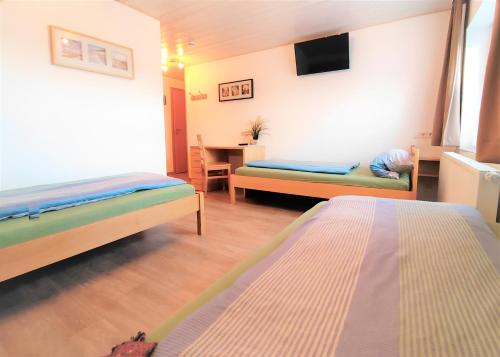 a room with two beds and a table with a tv at BodenSEE Haus am Geissbock in Meckenbeuren