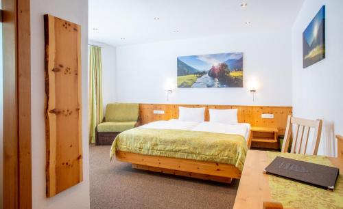 a bedroom with a bed and a desk with a chair at OLYMPIA Privathotel Garni in Sankt Jakob in Defereggen