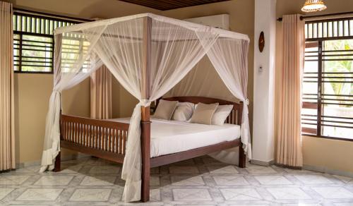 a bedroom with a canopy bed with white pillows at Villa Balapitiya Beach in Balapitiya