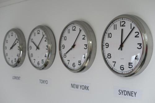 three clocks on a wall with different time zones at SMILE APPARTS - Appartements - Au coeur de Lorient - Au calme - Tout Confort in Lorient