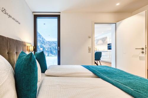 a bedroom with two beds and a large window at Alpin Apart Montafon in Sankt Gallenkirch