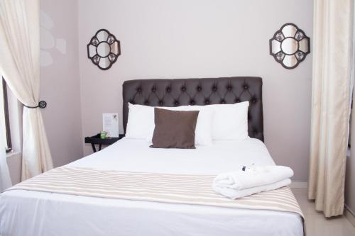 a bedroom with a white bed with a black headboard at Villa Prince in Harare