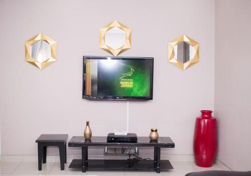 a living room with a table and a tv on a wall at Villa Prince in Harare