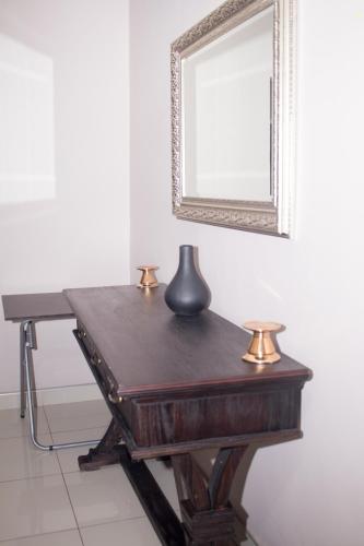 a wooden desk with a vase on it next to a mirror at Villa Prince in Harare