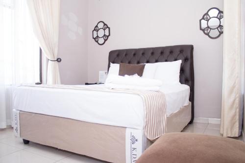 a bedroom with a large white bed with a black headboard at Villa Prince in Harare