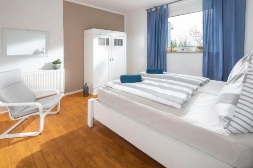 a white bed in a room with a chair and a window at Landliebe in Uchte