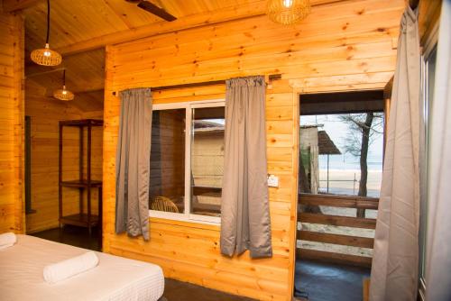 a log cabin with a bed and a window at Silent Beach Resort in Mandrem