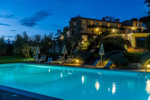 a swimming pool in front of a house at night at Relais Poggio Borgoni in San Casciano in Val di Pesa