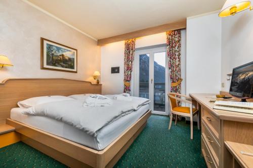 a hotel room with a bed and a desk at Albergo Contrin in Campitello
