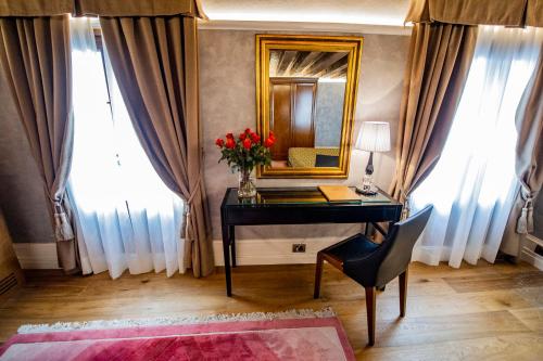 una scrivania con specchio e un vaso di fiori rossi di EGO' Residence Venice a Venezia