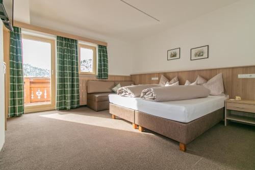 a bedroom with a bed and a couch and windows at S`Hoamatl in Obergurgl