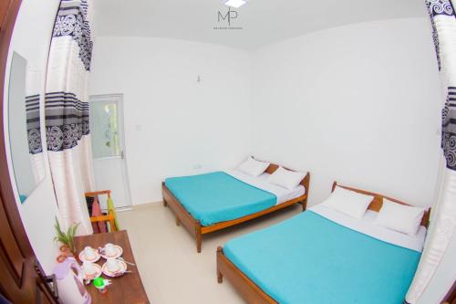 una habitación con 2 camas y una mesa con sidra de mesa en Tea Breeze Motel en Nallathanniya
