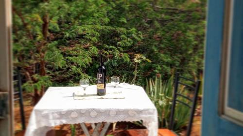 a table with a bottle of wine and glasses on it at FARINHA DE PAU - ECO B&B in Tarrafal