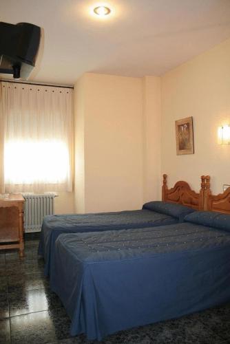 um quarto com uma cama com lençóis azuis e uma janela em Parque em Cazorla