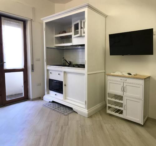 Habitación con armario blanco y TV en la pared. en Home Feeling Mascagni - Bilocale, en Alghero
