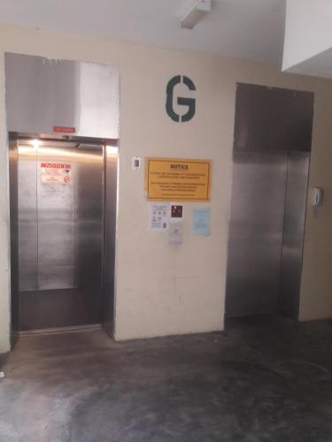 two silver elevators in a building with a sign on the wall at Jeffrey Homestay Ipoh U @ Lost World of Tambun in Tambun