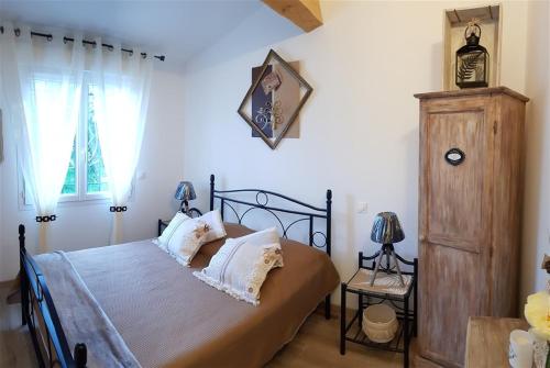 1 dormitorio con 1 cama con almohadas blancas y armario de madera en Villa T3 à 10' de Cassis SPA - Jacuzzi, en Carnoux