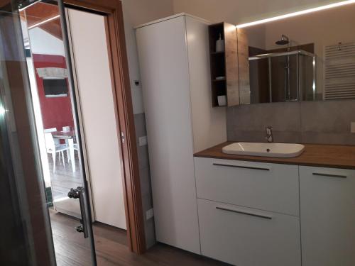 a white kitchen with a sink and a mirror at Ex Cinquantadue in Pasiano di Pordenone