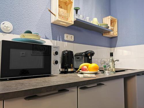 a kitchen with a microwave and a bowl of fruit on a counter at Hotel am Kurpark in Bad Lauterberg