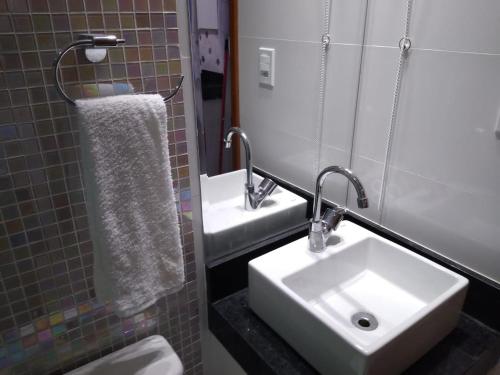 a bathroom with a sink and a toilet and a mirror at Apartamento Praia do Forte VIP in Cabo Frio