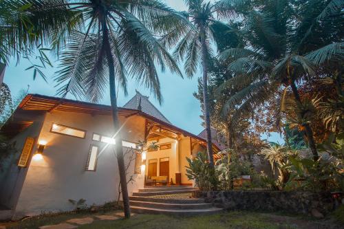 a house with palm trees in front of it at Adara Homestay in Banyuwangi