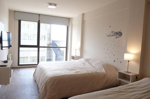 a bedroom with two beds and a large window at Brc Apartment in San Carlos de Bariloche
