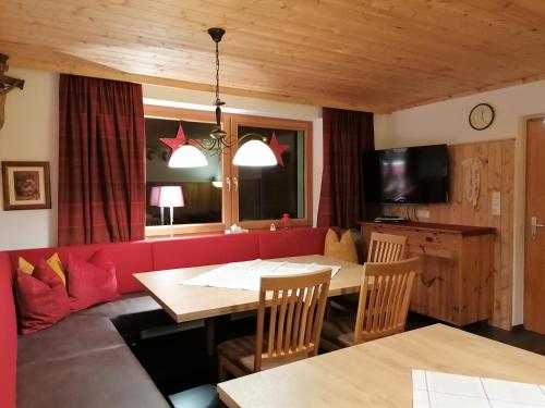 a living room with a table and a red couch at Ferienhaus Sonnhof am Walchsee in Kössen