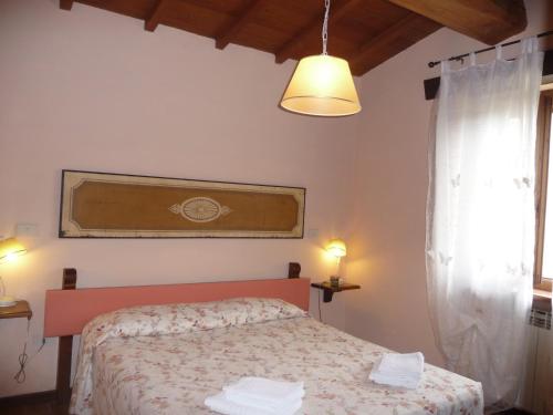 プラトヴェッキオにあるMAGNOLIA TUSCANY HOUSE WITH POOL Agriturismo Poppienaのベッドと窓のある小さな寝室