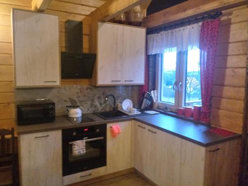 a kitchen with white cabinets and a sink and a window at Domek Na Skarpie in Zubrzyca Dolna