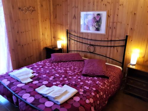 una camera da letto con letto, lenzuola e asciugamani viola di Relax Cinque Confini a Terminillo