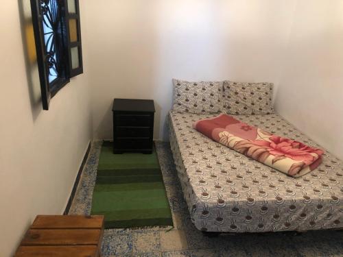 a small bedroom with a bed and a table at Surf and Skate hostel taghazout in Taghazout