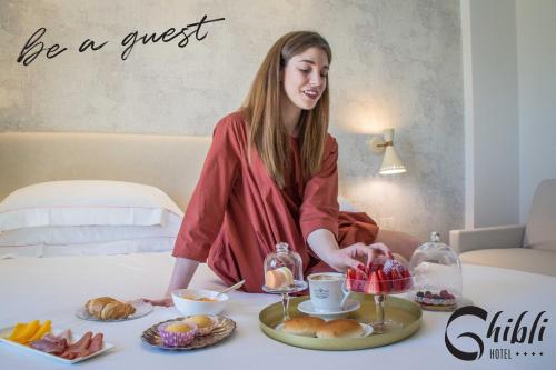 une femme assise à une table avec un plateau de nourriture dans l'établissement Ghibli Hotel, à Civitanova Marche