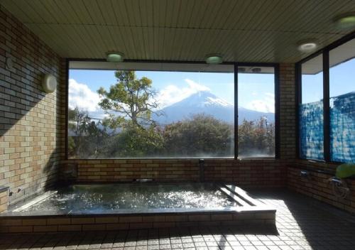 baño con vistas a la montaña a través de una ventana en kawagutiko station inn / Vacation STAY 63735, en Azagawa